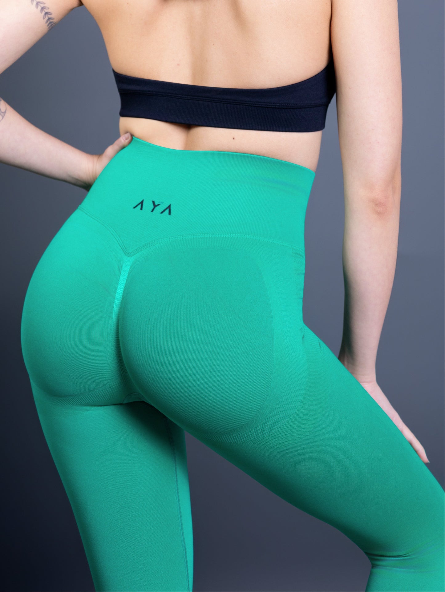 Close-up of woman wearing bright green AYA seamless leggings – high-waisted sculpting design that lifts and defines the glutes, combining performance and style.