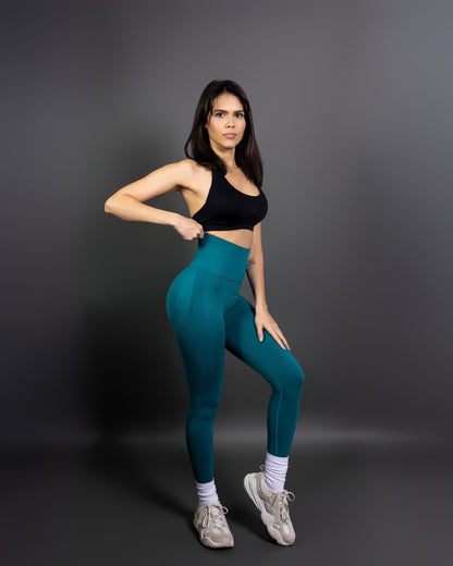 Woman wearing teal high-waisted seamless leggings and black sports bra – sculpting, stretchy gym leggings designed to accentuate curves and provide maximum comfort during workouts