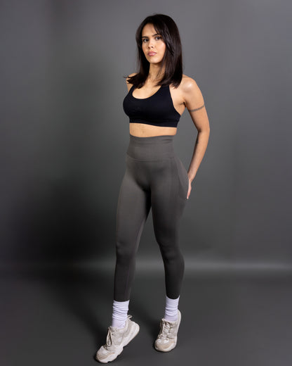 Woman wearing charcoal grey high-waisted seamless leggings and black sports bra – minimalist, body-contouring activewear for training and everyday movement.
