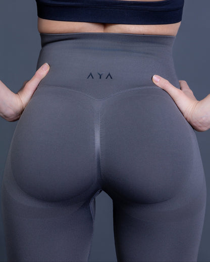 Woman wearing charcoal grey high-waisted seamless leggings and black sports bra – minimalist, body-contouring activewear for training and everyday movement.