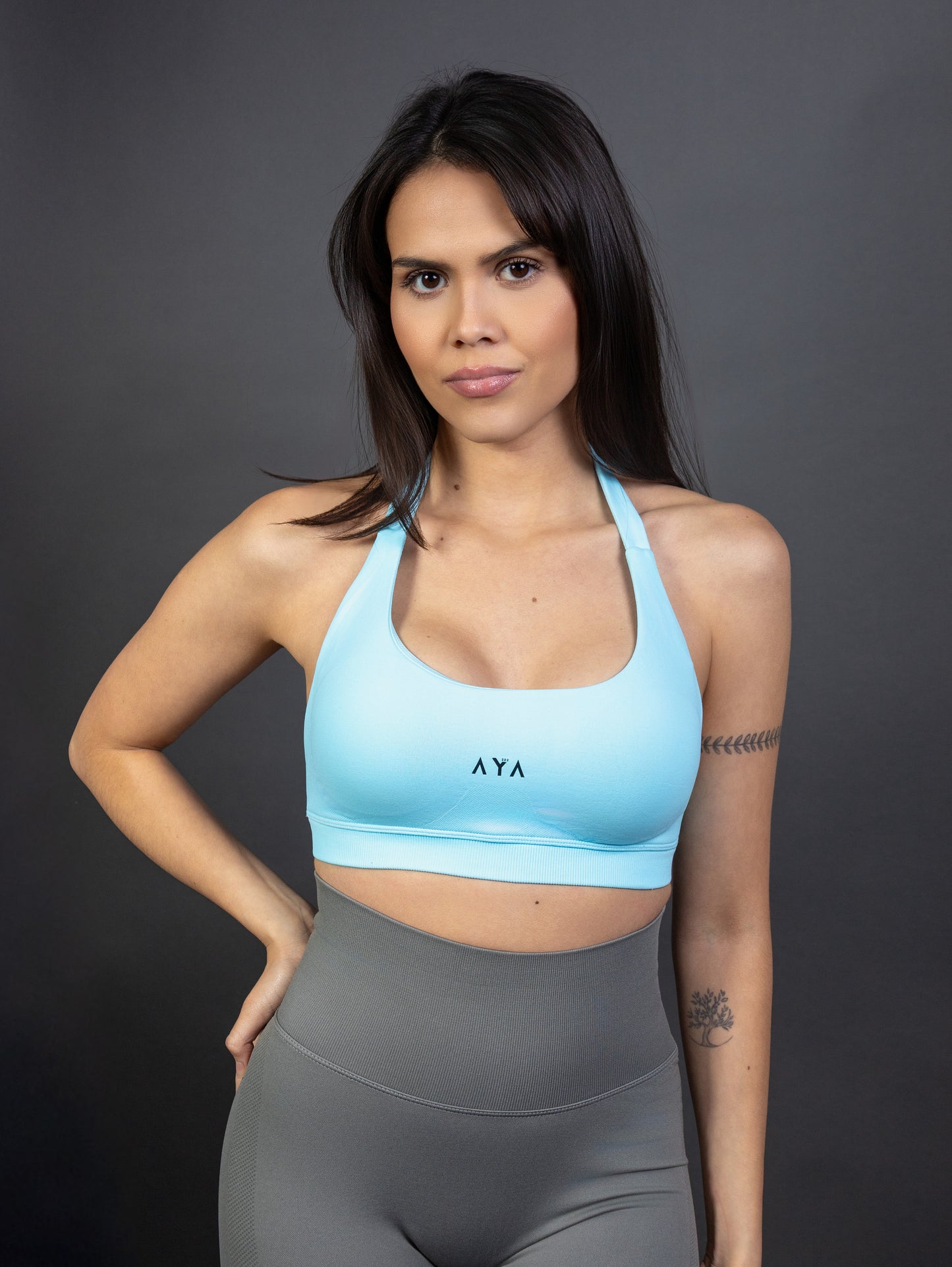 Front view of woman wearing white AYA halter sports bra and grey seamless leggings – clean, minimal activewear designed for a confident and modern feminine look.