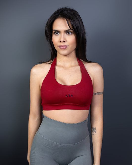 Close-up of woman wearing red AYA halter sports bra and grey seamless leggings – bold, empowering activewear that highlights confidence, strength, and feminine allure.