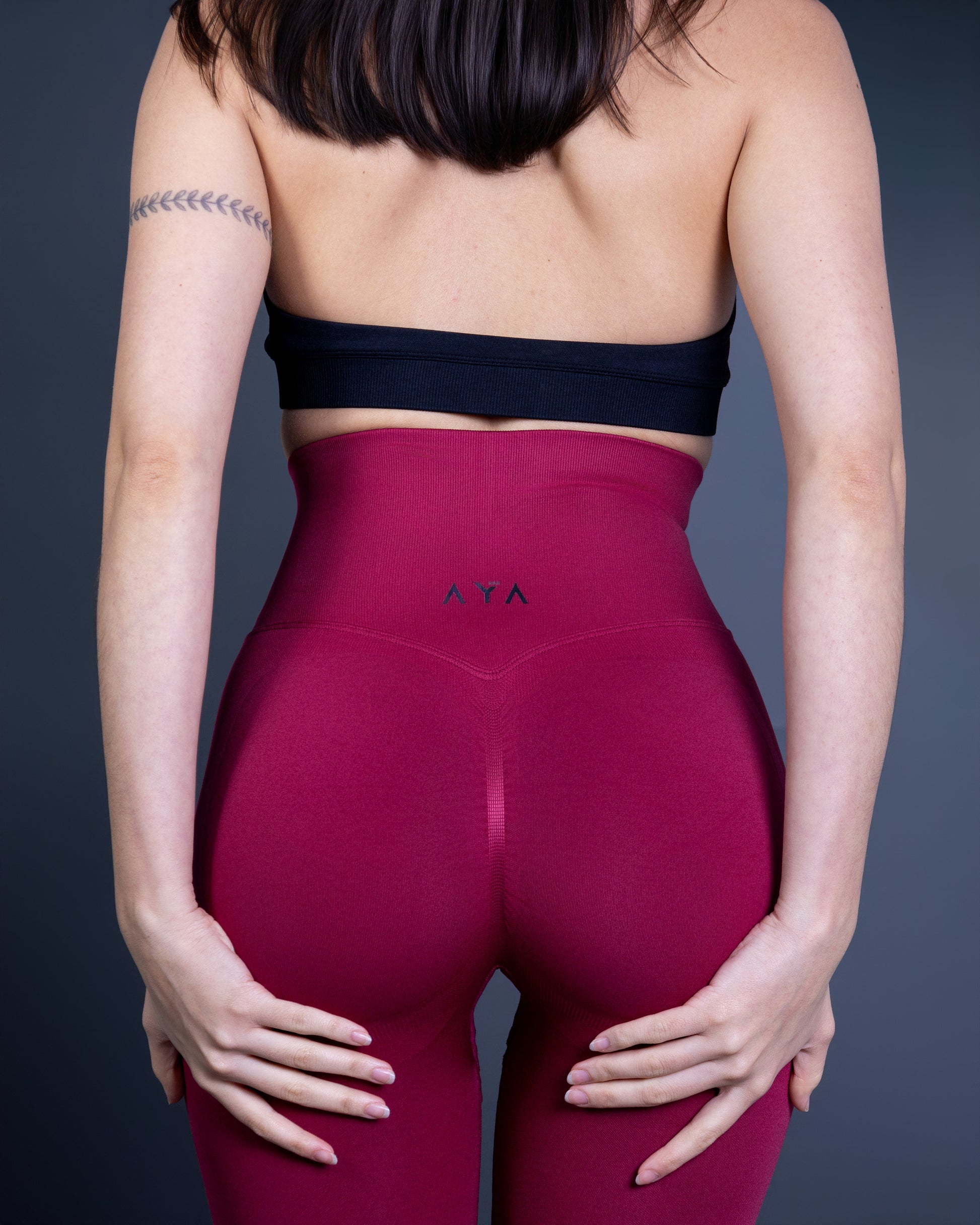 Woman wearing deep red high-waisted seamless AYA leggings and black sports bra – bold, sculpting activewear that enhances curves and radiates confidence.