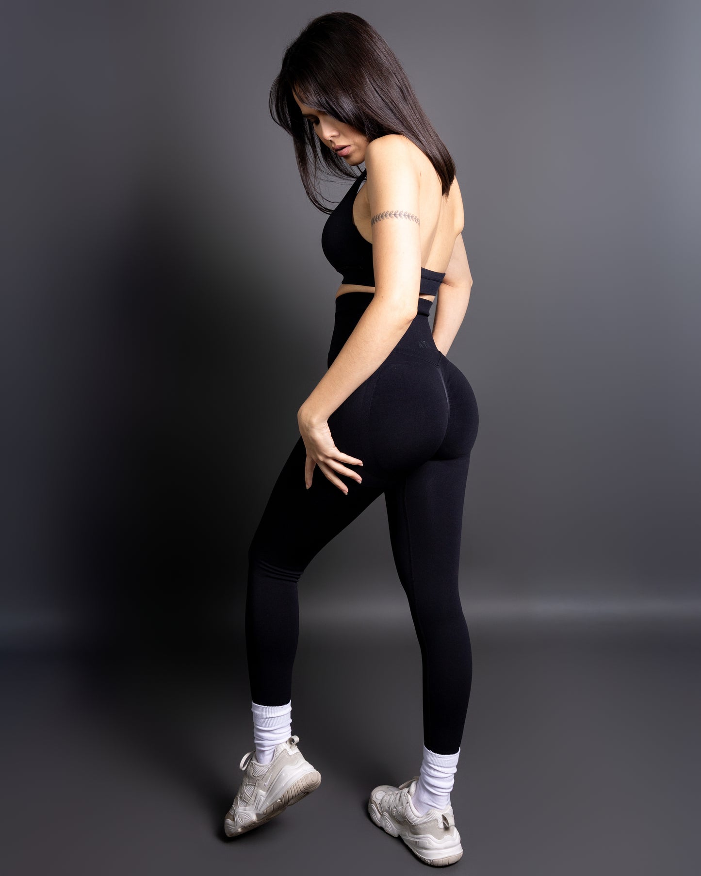 Woman wearing black high-waisted seamless leggings and sports bralette – figure-hugging push-up leggings for gym and everyday wear