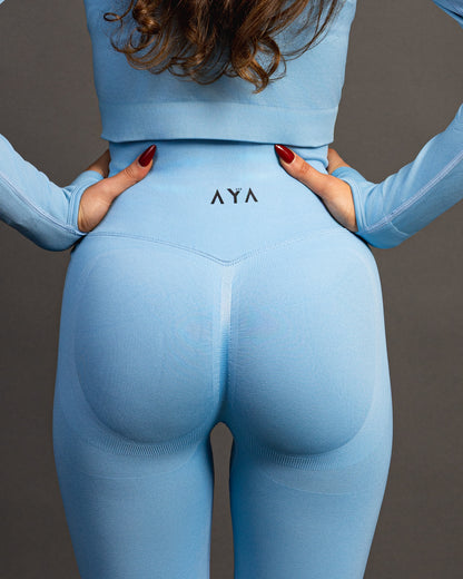 Woman wearing baby blue high-waisted seamless AYA leggings and black sports bra – sleek, body-hugging fit designed to enhance natural curves and exude quiet confidence.