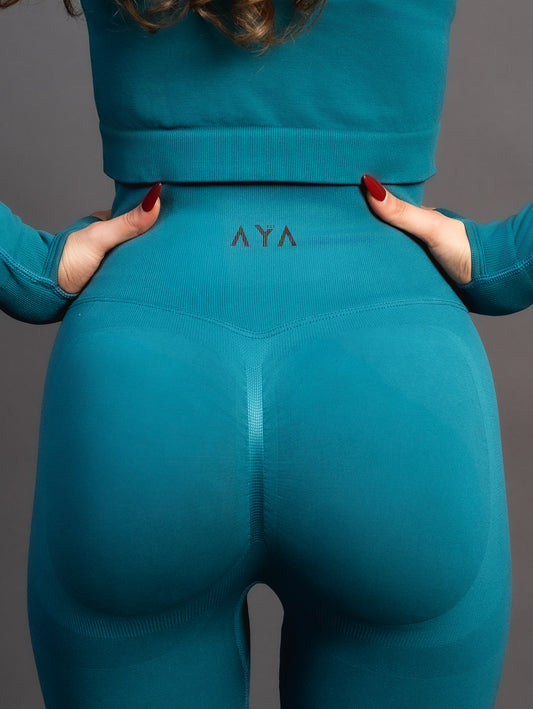Woman wearing teal high-waisted seamless leggings and black sports bra – sculpting, stretchy gym leggings designed to accentuate curves and provide maximum comfort during workouts