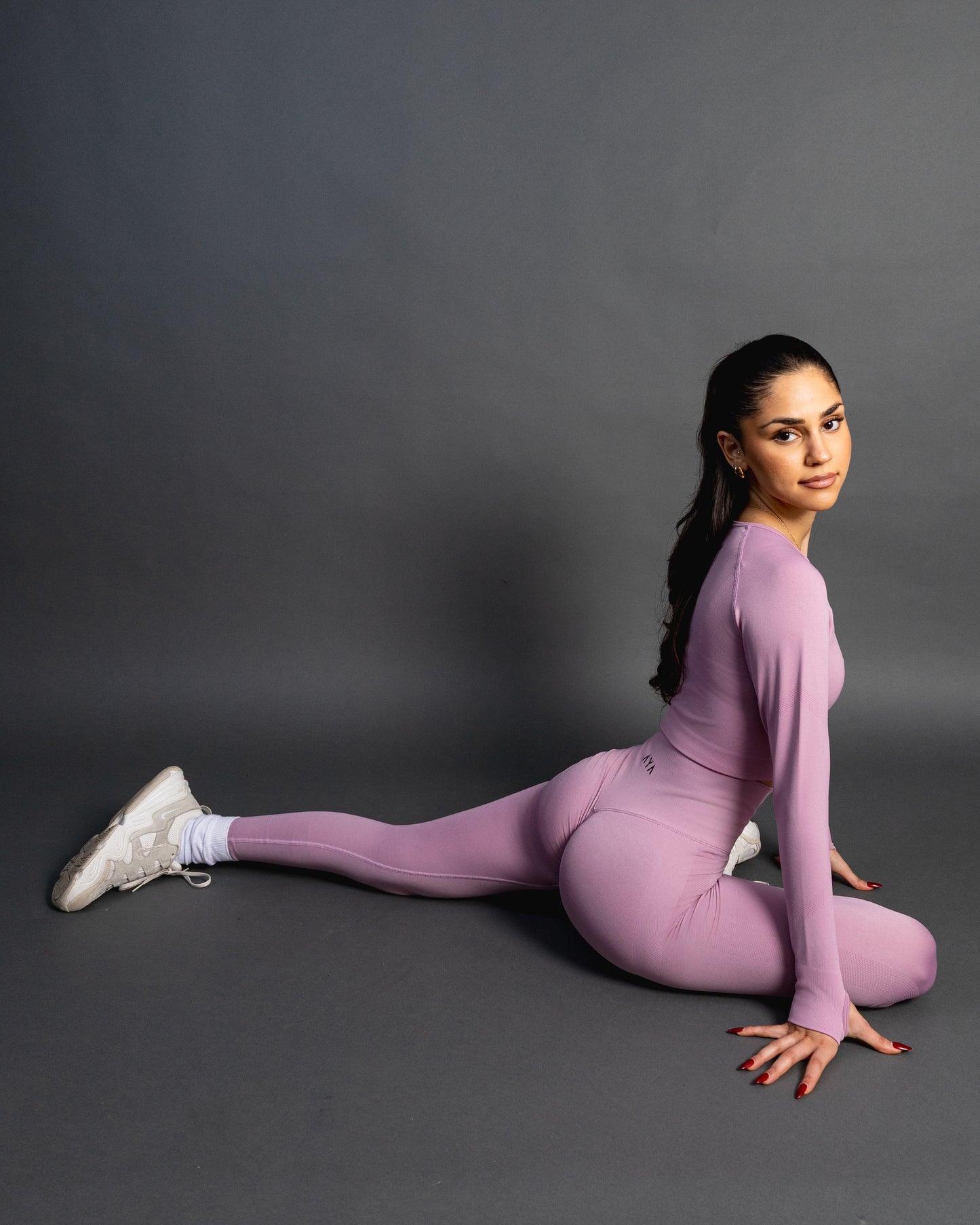 Woman wearing baby pink high-waisted seamless AYA leggings and black sports bra – sleek, body-hugging fit designed to enhance natural curves and exude quiet confidence.
